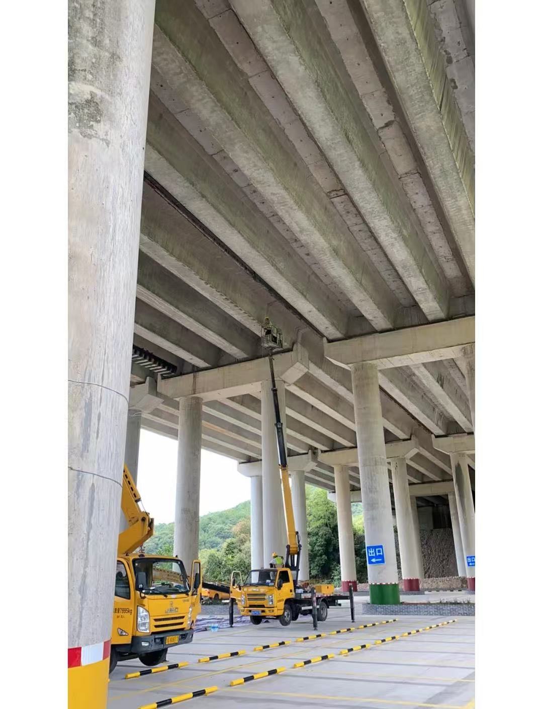 桥梁梁底碳纤维加固施工现场，作业人员进行基层与材料施工